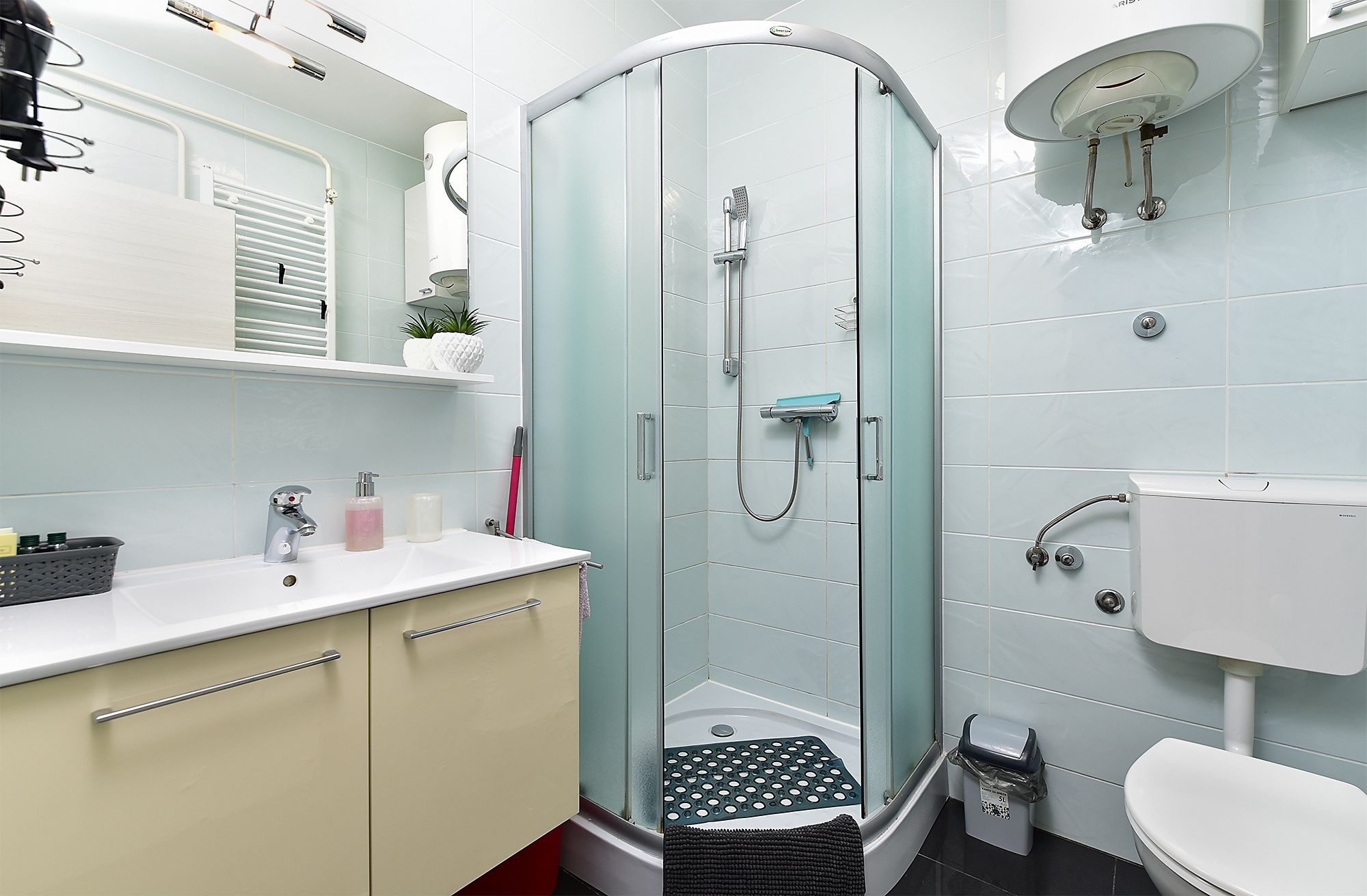 Ein modernes Badezimmer mit einer gläsernen Dusche, einem weißen Waschbecken und einer Toilette.