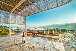 Un espace extérieur aménagé avec une table, des chaises et une bouteille de vin.