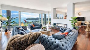 A spacious living room with large windows, a fireplace, and modern furniture.
