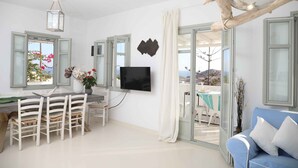 Ein modernes Wohnzimmer mit Essbereich, einem Flachbildfernseher und Blick ins Freie.