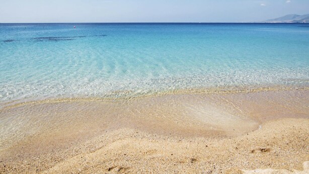 Ein Strand mit klarem, flachen Wasser und einem Sandufer.
