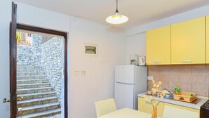 Una cocina compacta con armarios amarillos, un refrigerador blanco y un comedor con mesa y sillas.