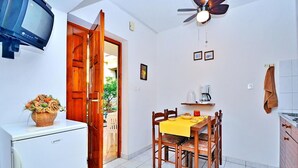 Une cuisine de taille réduite avec un coin repas, un ventilateur de plafond et un téléviseur.