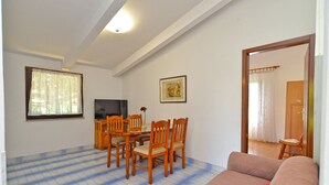 A living room with a sofa, a dining table with chairs, a TV, and a framed picture on the wall. - Apartment 667/1581 (Istria - Medulin), 300m from the beach (Medulin)