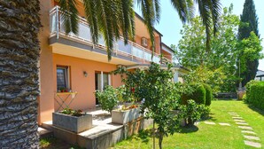A two-story building with a balcony, stone steps leading to the entrance, and a well-maintained garden with a lawn and various plants. - Apartment 667/1581 (Istria - Medulin), 300m from the beach (Medulin)