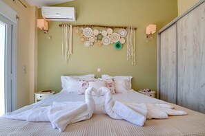A neatly made bed with white linens and towels arranged in a swan shape, a wall-mounted decorative piece, and a wooden wardrobe.