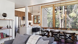 Eine moderne Küche mit Holzausstattung, einem Edelstahlkühlschrank und einem Essbereich mit Holztisch und Stühlen.