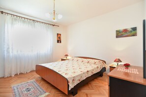 A bedroom with a wooden bed, a desk, two lamps, a painting, and a patterned rug.