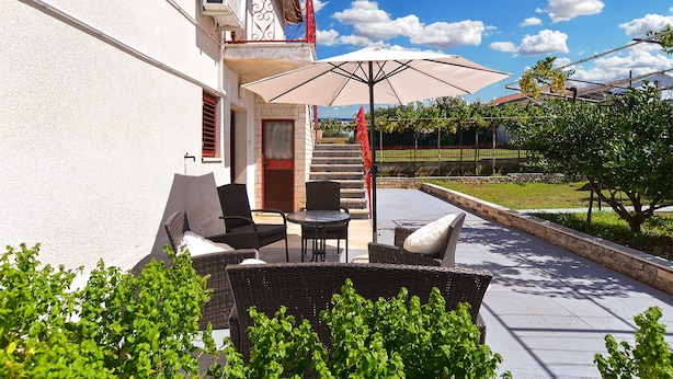 An outdoor patio with wicker furniture, a large umbrella, and a staircase leading to a balcony. - Apartment 684/1615 (Istria - Stinjan), 400m from the beach (Stinjan)