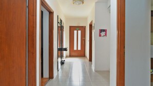 A hallway with wooden doors, a tiled floor, and a door with a green exit sign. - Apartment 684/1615 (Istria - Stinjan), 400m from the beach (Stinjan)