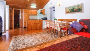 A cozy interior with a wooden ceiling, a dining area with a table and chairs, a kitchen with wooden cabinets, and a living area with a sofa and a painting on the wall. - Apartment 692/1629 (Istria - Premantura), 450m from the beach (Premantura)