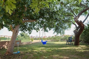 Relax in a serene outdoor space with a sturdy tree-supported swing and a nearby seating area.