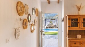Una habitación con vista a una piscina y montañas, decorada con obras de arte en la pared y un aparador de madera.