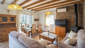 Una sala de estar acogedora con vigas de madera, chimenea, comedor y televisor.