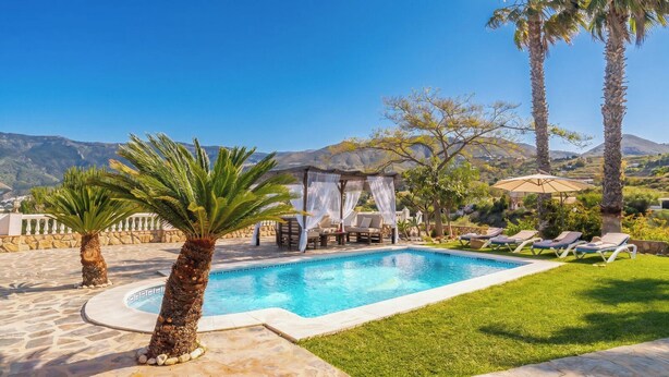 Una piscina con una pérgola, palmeras y sillas de descanso.