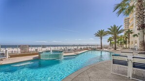 A pool area with a hot tub, lounge chairs, and a view of the ocean. - Luxury Beachfront 4BR/4BA Condo Sleeps 13 with Stunning Views and Large Balcony (Orange Beach)