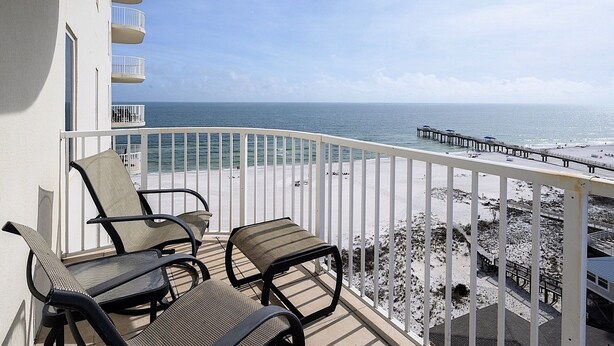 A balcony with two chairs and a view of the beach and pier. - Luxury Beachfront 4BR/4BA Condo Sleeps 13 with Stunning Views and Large Balcony (Orange Beach)