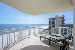 A balcony with a view of the ocean and a building in the background.