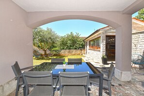 An outdoor patio with a table and chairs, a hammock, and a stone wall.
