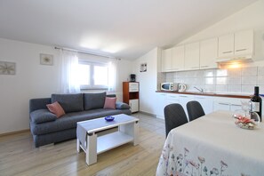 A compact living space with a sofa, a small table, a kitchenette with white cabinets, and a dining area with a table and chairs. - Apartment 719/1675 (Istria - Stinjan), 950m from the beach (Stinjan)