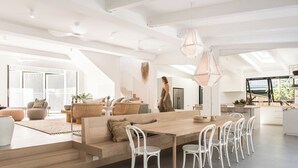 Una cocina amplia y moderna con una mesa de comedor de madera, sillas blancas e iluminación colgante.