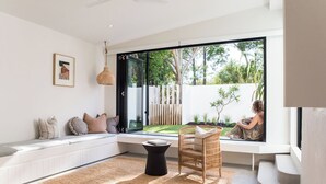 Una sala de estar moderna con un ventanal grande, un banco empotrado, una silla de mimbre y una mesita.