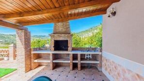 Zona de barbacoa de ladrillo al aire libre con un lavadero y un pergolado de madera.