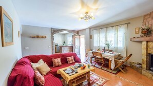 A cozy living room with a red sofa, a dining table set for four, and a fireplace.