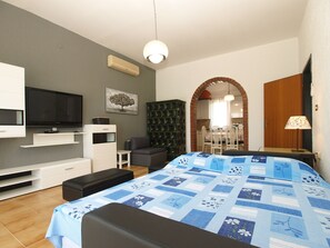 A modern bedroom with a bed, a TV, a bookshelf, and a dining area visible through an archway. - House 747/1746 (Istria - Stinjan), 1000m from the beach (Stinjan)