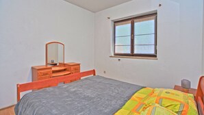 Ein Schlafzimmer mit einem Bett, einem Schminktisch, einem Spiegel und einem Fenster.