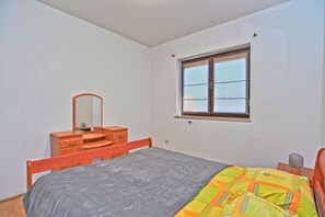 Un dormitorio con cama, cómoda, espejo y ventana.