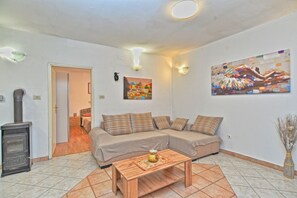 Una sala de estar con un sofá, una mesa de centro de madera, una chimenea y dos lámparas fijadas a la pared.