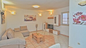 Ein Wohnzimmer mit Sofa, Couchtisch, Fernseher und Kunstwerken.