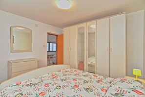 A bedroom with a bed, a wardrobe, a mirror, and a window.