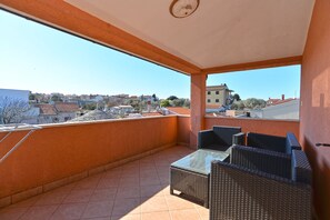 A balcony with wicker furniture and a clear view of the surrounding buildings.