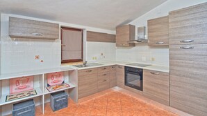 Cozinha moderna com armários brancos, pia de aço inoxidável e lava-louças.