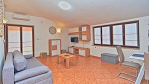 Sala de estar com sofá, mesa de centro, TV e espaço para escritório.