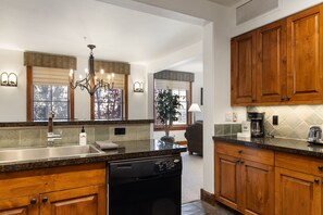 A kitchen with wooden cabinets, a dishwasher, a coffee maker, and a toaster.