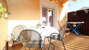 An outdoor patio with a table and chairs, a covered area, and a wooden fence. - Apartment 768/1789 (Istria - Fažana), 500m from the beach (Fažana)