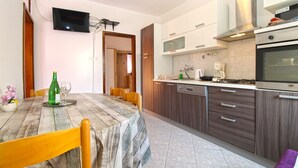 A modern kitchen with wooden cabinets, a built-in oven, and a dining area with a table and chairs. - Apartment 768/1789 (Istria - Fažana), 500m from the beach (Fažana)