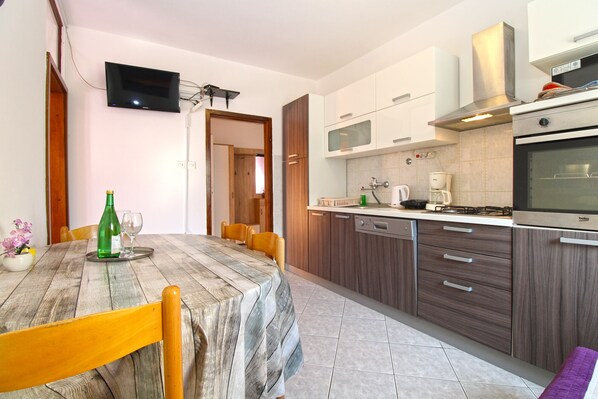 A modern kitchen with wooden cabinets, a built-in oven, and a dining area with a table and chairs.