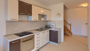 A modern kitchen with white cabinets, a built-in oven, a sink, and a coffee maker. - Apartment 771/1799 (Istria - Fažana), 300m from the beach (Fažana)