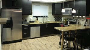 A modern kitchen with black cabinets, stainless steel appliances, a wooden countertop, and a bar area with stools. - La Cassita Beautiful Condo WOW!!!! (Las Vegas)