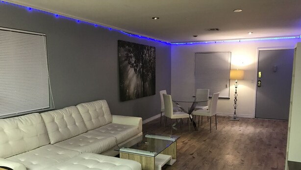 A modern living room with a white leather sofa, a glass coffee table, and a dining area with white chairs. - La Cassita Beautiful Condo WOW!!!! (Las Vegas)
