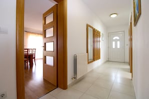 A hallway with a wooden door, a radiator, and a mirror on the wall.
