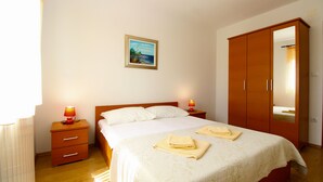 A bedroom with a bed, bedside lamps, a wardrobe, and a painting on the wall. - Apartment 777/1811 (Istria - Fažana), 500m from the beach (Fažana)