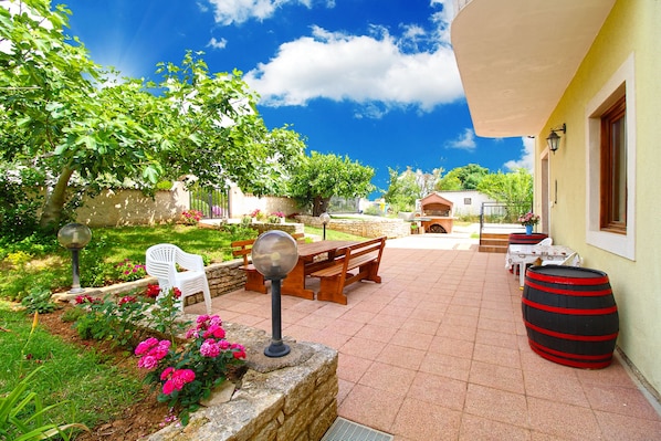 A patio with a table and chairs, a barbecue grill, and a barrel.