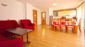 A living room with a wooden table and red chairs, a kitchen with wooden cabinets, and a dining area with a table and chairs. - Apartment 777/1811 (Istria - Fažana), 500m from the beach (Fažana)