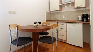 A compact kitchen with a round table, four chairs, a coffee maker, and a dishwasher.