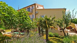 A two-story building with balconies, surrounded by lush greenery and a well-maintained garden.